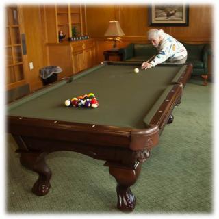 A person aiming at the cue ball on a pool table in a cozy room.