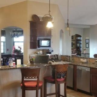 A modern kitchen with bar seating and pendant lights.