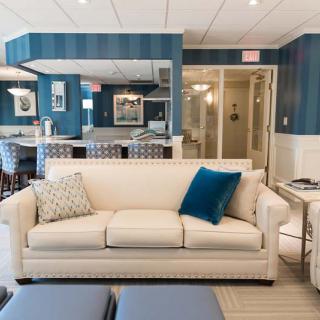 A modern living room with a beige sofa and blue accents, featuring bright lighting and contemporary decor.