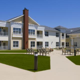 A modern residential building with a well-maintained lawn and outdoor seating area.