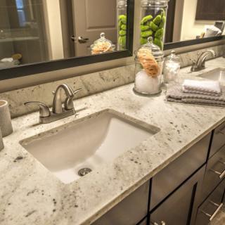 A modern bathroom with a sleek sink and countertop decorated with towels and decorative items.