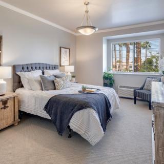 A modern and elegantly decorated bedroom with a comfortable bed, stylish furniture, and ample natural light.