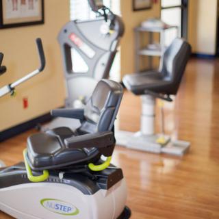 A gym with various exercise equipment arranged neatly on a polished wooden floor.