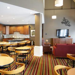A modern dining and living area with wood furniture and a striped carpet.