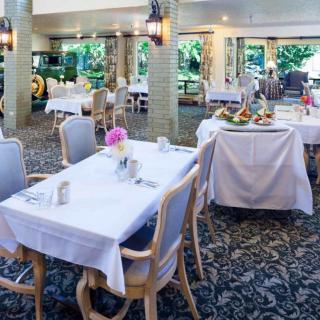 A well-lit restaurant dining area with neatly set tables covered in white tablecloths.