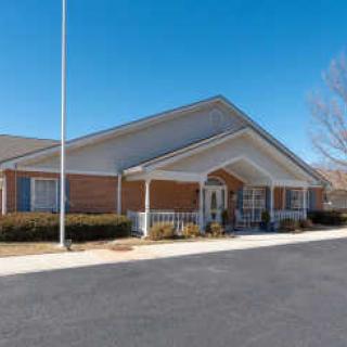 A brick building with a covered entrance and a flagpole, under a clear blue sky.