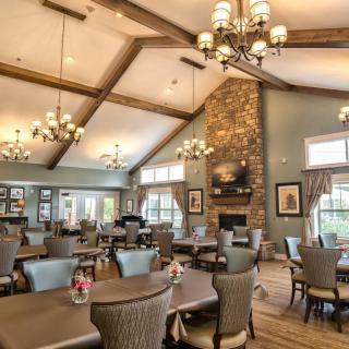 A spacious dining room with elegant chandeliers, a stone fireplace, and comfortable seating.
