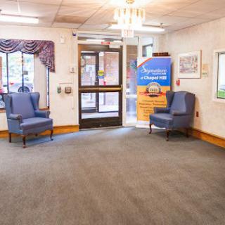 A spacious lobby with chairs and a sign near the entrance.