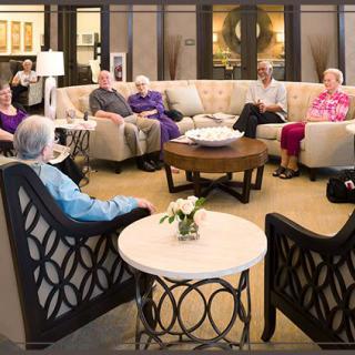 A group of seniors gather in a cozy living room for a conversation.