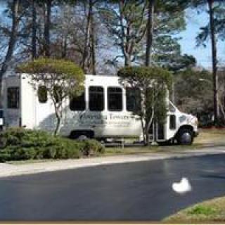 A shuttle bus parked on a road surrounded by trees.