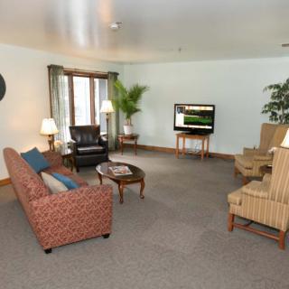 A spacious living room with a sofa, armchairs, and a television.