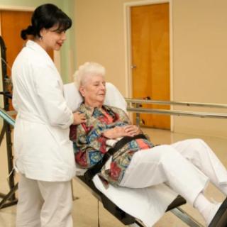 A healthcare worker assisting an elderly woman during a physical therapy session.