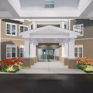 A welcoming entrance to a modern residential building, featuring elegant architecture and landscaped flower beds.