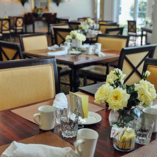 A beautifully set restaurant dining area with flowers on the tables.