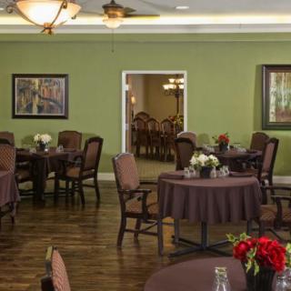 A dining area with neatly arranged tables, comfortable chairs, and decoratively painted green walls.