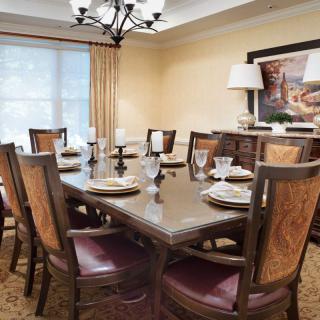 A well-decorated dining room with a large table and chairs, featuring elegant place settings and a chandelier.