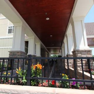A building entrance with a ramp and colorful flowers lining the pathway.