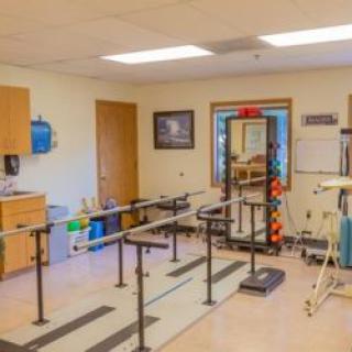 A physical therapy room equipped with parallel bars and medical exercise equipment.