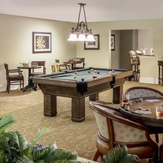 A cozy recreation room featuring a pool table and comfortable seating areas with framed art on the walls and elegant lighting.