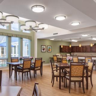 A modern dining room with several tables and chairs, featuring large windows and stylish lighting.