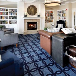 A cozy library room featuring bookshelves, a fireplace, and comfortable seating.