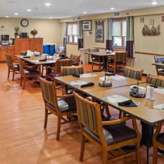 A spacious dining area with neatly arranged tables and chairs on a wooden floor.