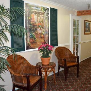 A cozy hallway with wicker chairs, a potted plant on a small table, and a decorative painting on the wall.