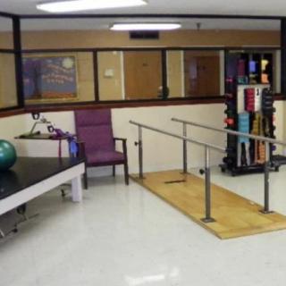 A physical therapy room equipped with parallel bars and exercise equipment.