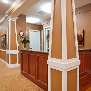A warmly decorated reception area with wooden paneling and ornamental columns.
