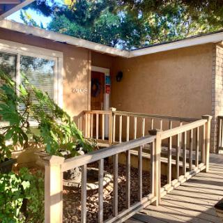 A welcoming entrance featuring a wooden ramp surrounded by greenery.