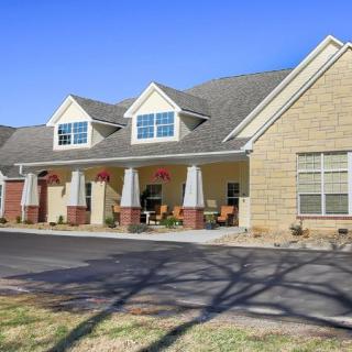 A large residential house with a front porch and multiple windows under a clear blue sky.