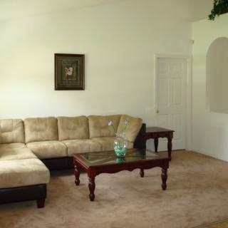A cozy living room with a sectional sofa, wooden coffee table, and framed artwork on the wall.