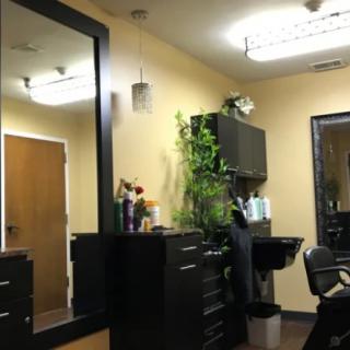 A cozy salon interior with a large mirror, cabinets, and decorative plants.