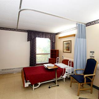 A view of a hospital room featuring a bed, chair, and window.