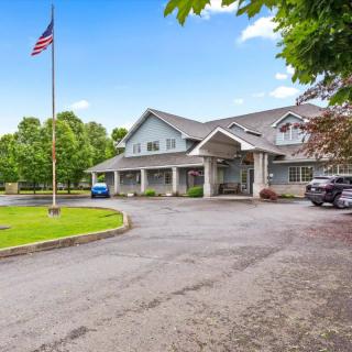 A building with a prominent entrance and an American flag in front, surrounded by trees and a parking area.
