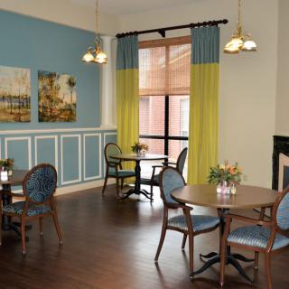 A cozy dining area with elegant tables, chairs, and decorative paintings on the wall.