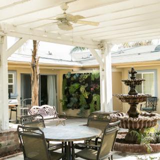 A serene outdoor patio with a fountain, seating area, and lush greenery.