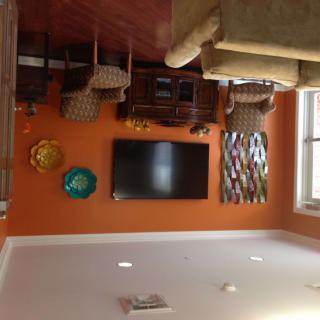 A cozy living room with an orange accent wall featuring a mounted television and decorative wall art.