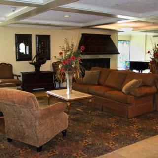 A comfortable living room with sofas, armchairs, and a coffee table, featuring elegant decor and warm lighting.