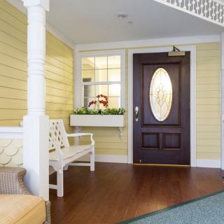 A welcoming entrance with a dark wooden door and yellow siding.