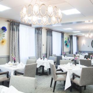 A beautifully decorated restaurant dining area with elegantly set tables and a chandelier.