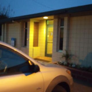 A dimly lit entrance of a building with a parked car in the foreground.