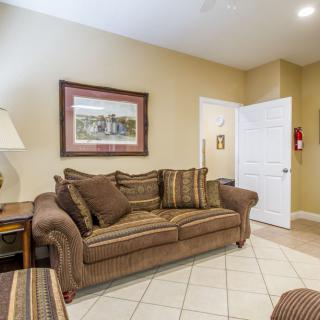 A cozy living room with a brown sofa, lamp, and wall art.