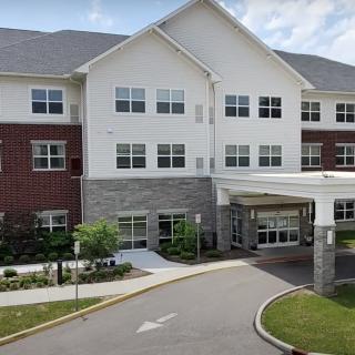 A modern multi-story residential building with a landscaped entrance.
