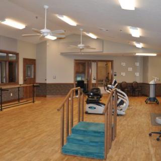 A physical therapy room with exercise equipment and a wooden floor.