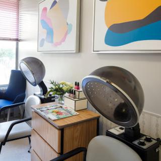 A cozy hair salon featuring vintage hair dryers and modern artwork.
