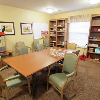 A cozy meeting room with a conference table, chairs, and bookshelves filled with books and games.