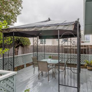 A cozy outdoor patio space with a gazebo sheltering a table and chairs on a deck.