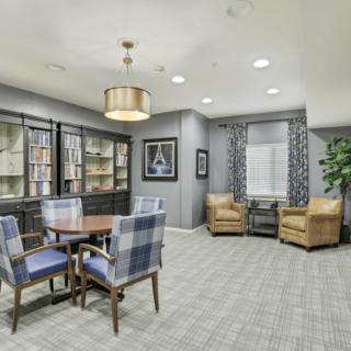 A cozy living room with a table and chairs, bookshelves, and comfortable seating.