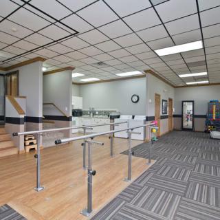 A rehabilitation clinic with exercise equipment and parallel bars for physical therapy.